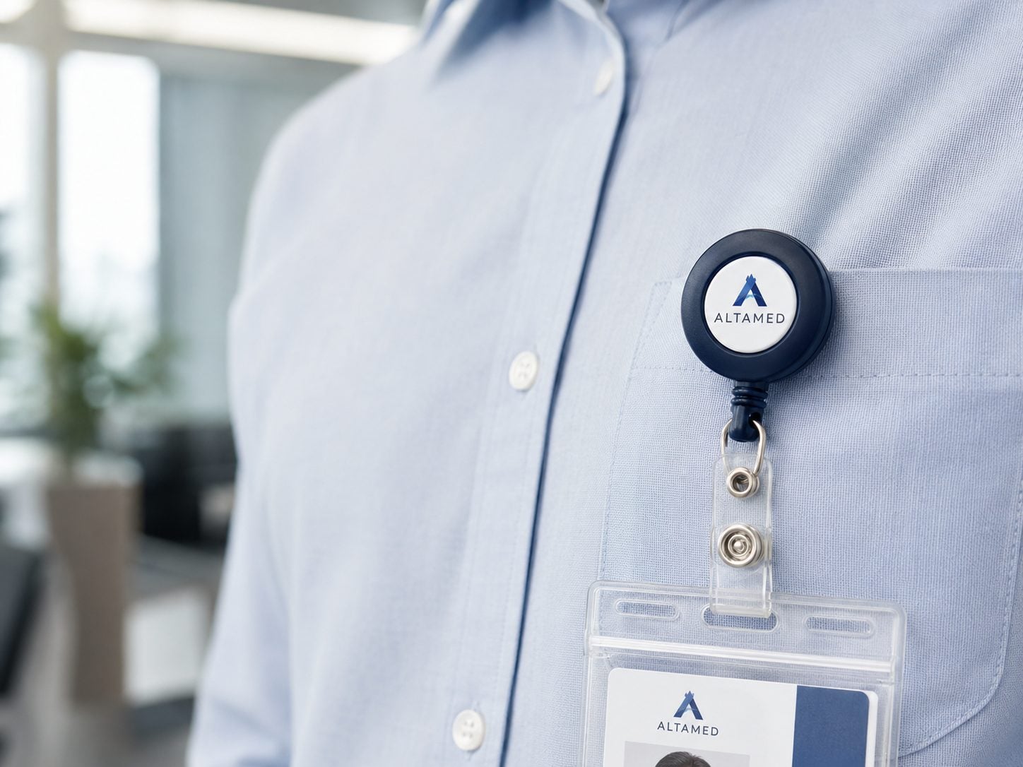 Full-color printed round retractable badge reel with an invented brand logo clipped to an office ID lanyard